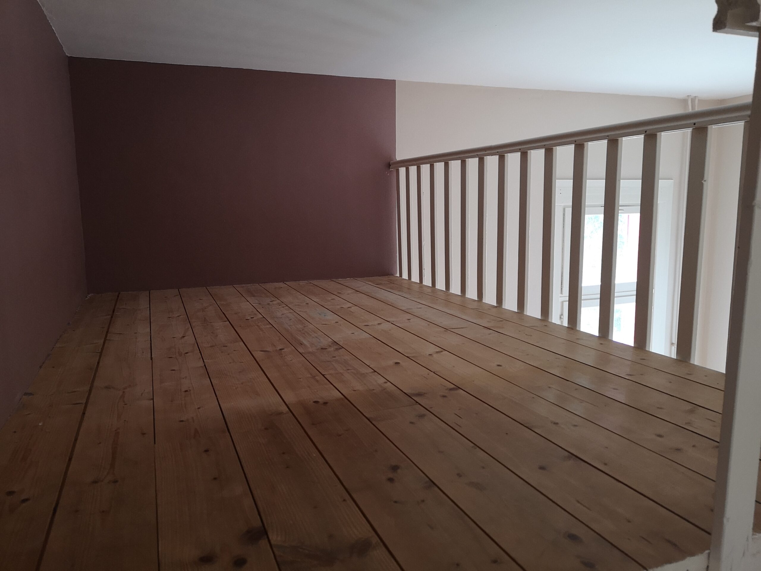 Coin mezzanine avant aménagement, le sol est en bois brut, chaleureux