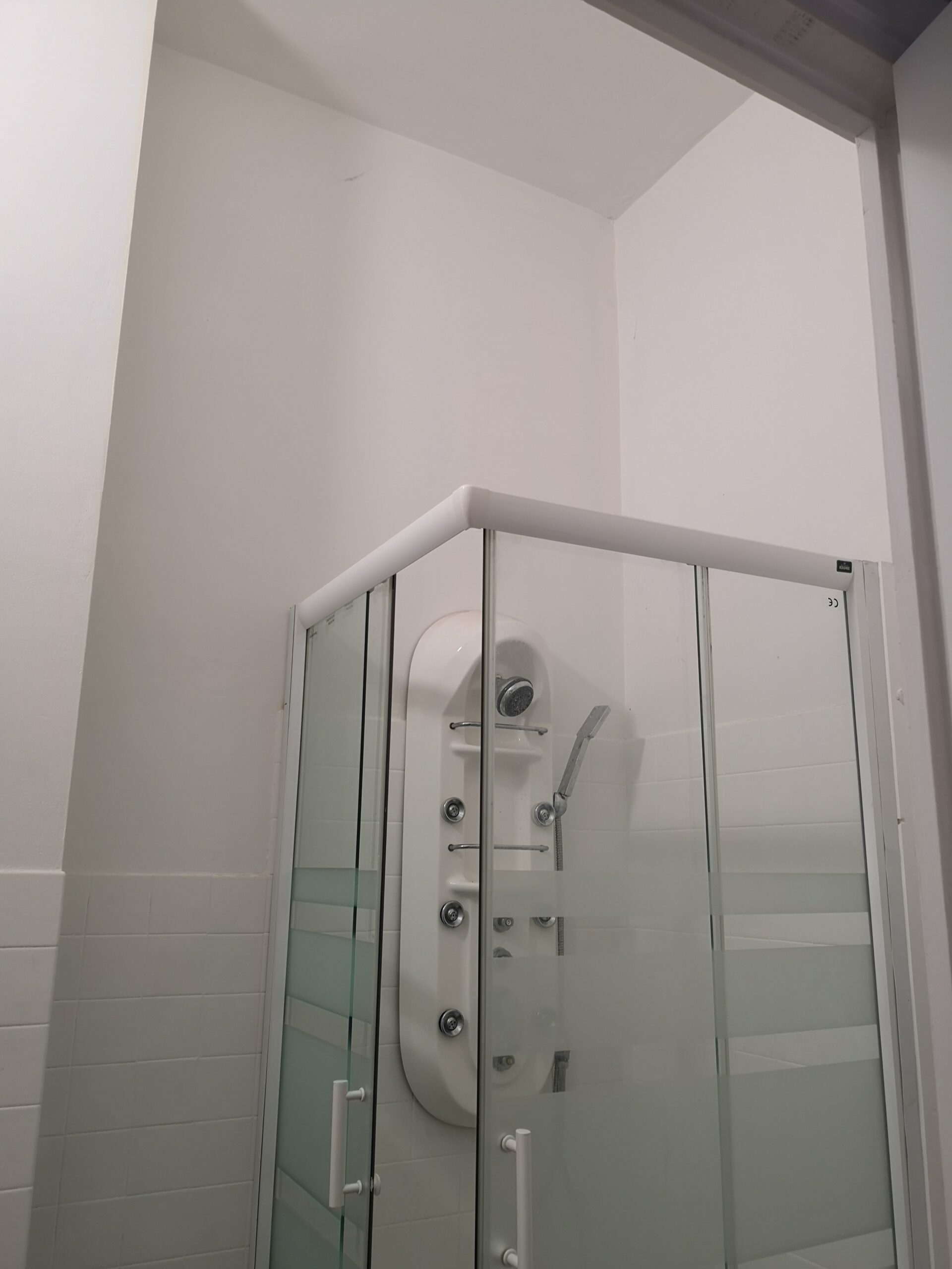 Salle d'eau du studio mezzanine avant aménagement, le haut plafond et la pièce toute blanche sont un peu oppressants