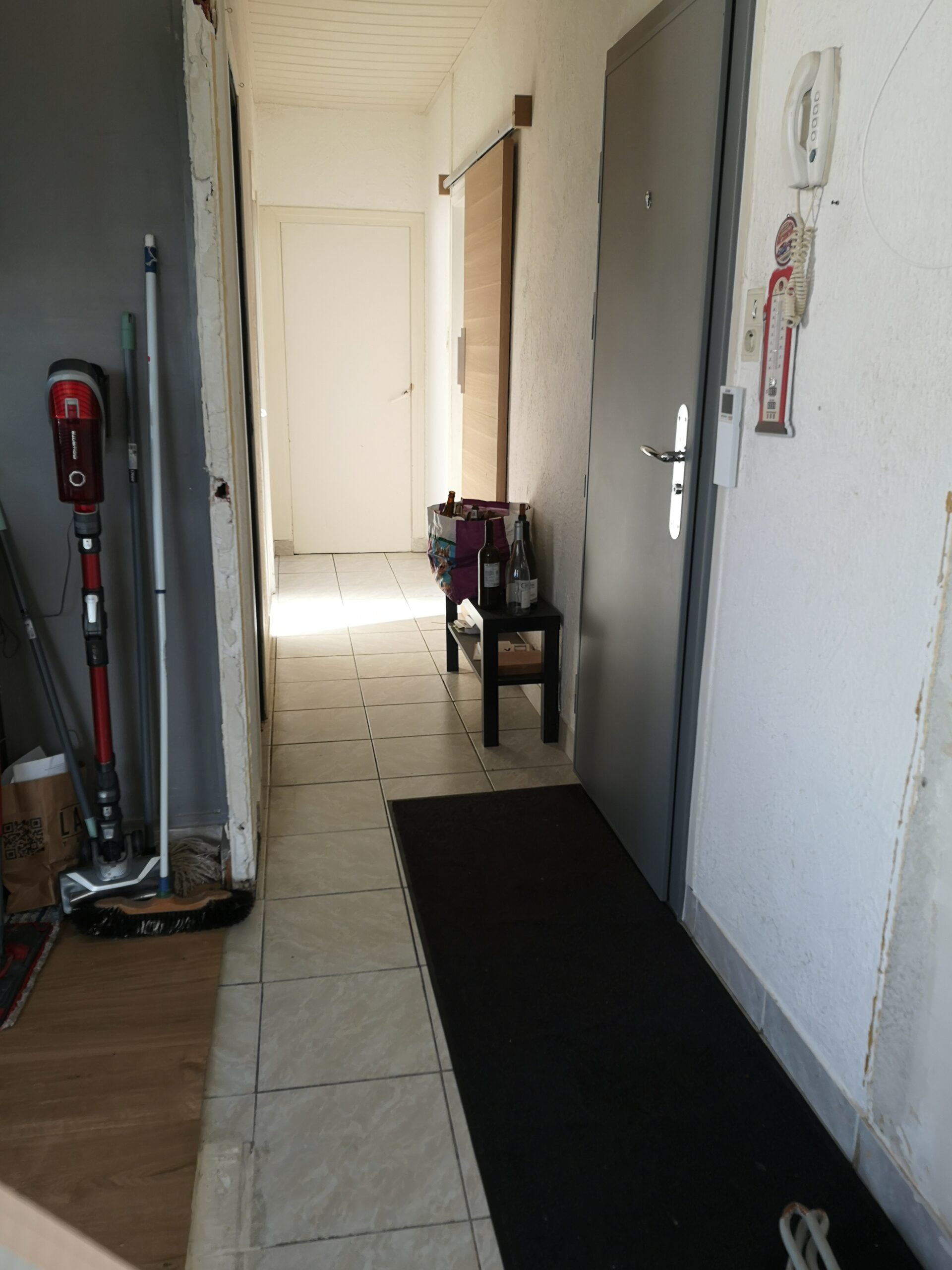 Couloir avant travaux : sols dépareillés, crépis aux murs et plafond en lambris