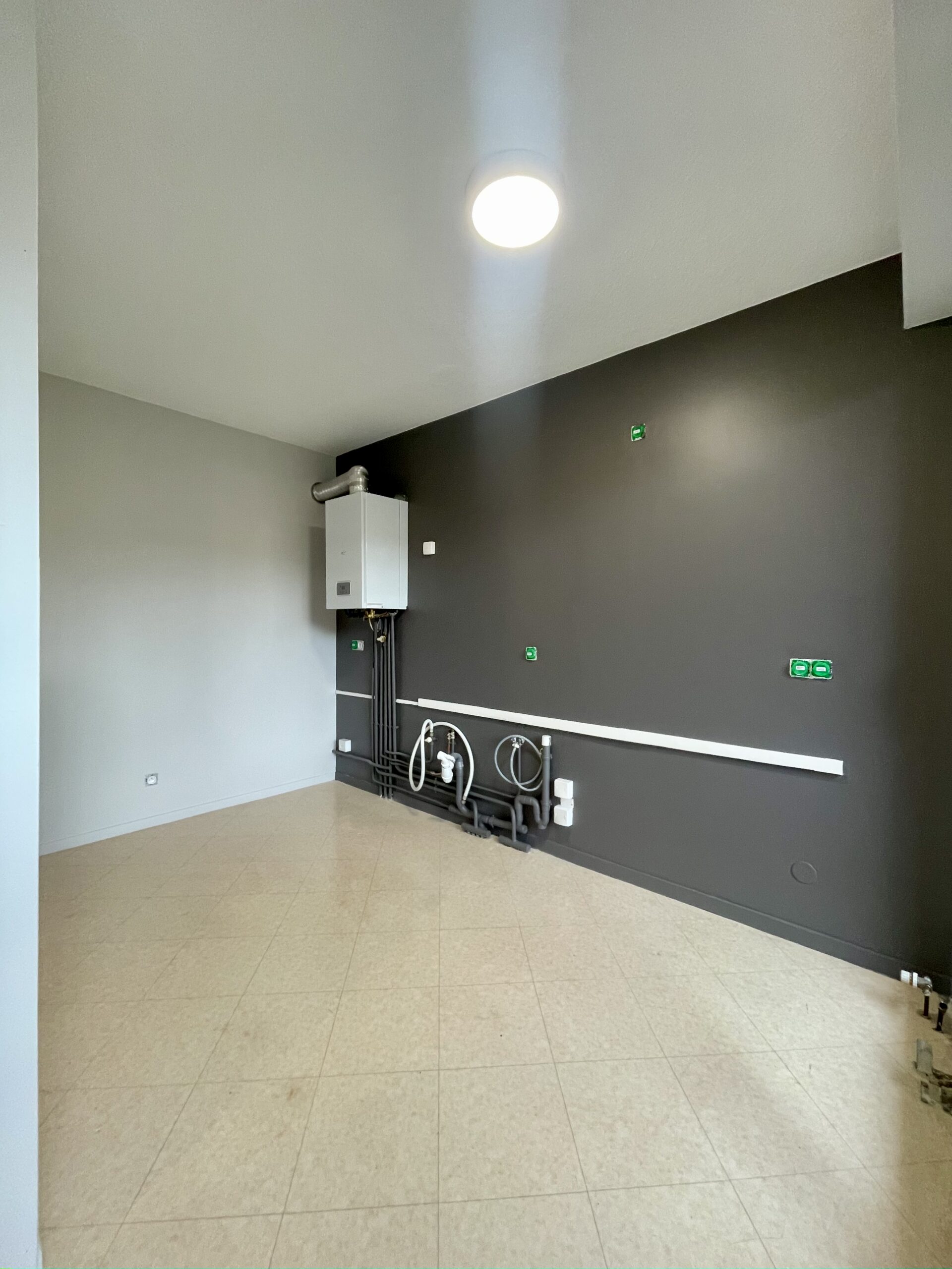 les murs de la cuisine ont été peints en gris clair et un mur d'accent a été peint en gris foncé, la cuisine sera installée par la suite