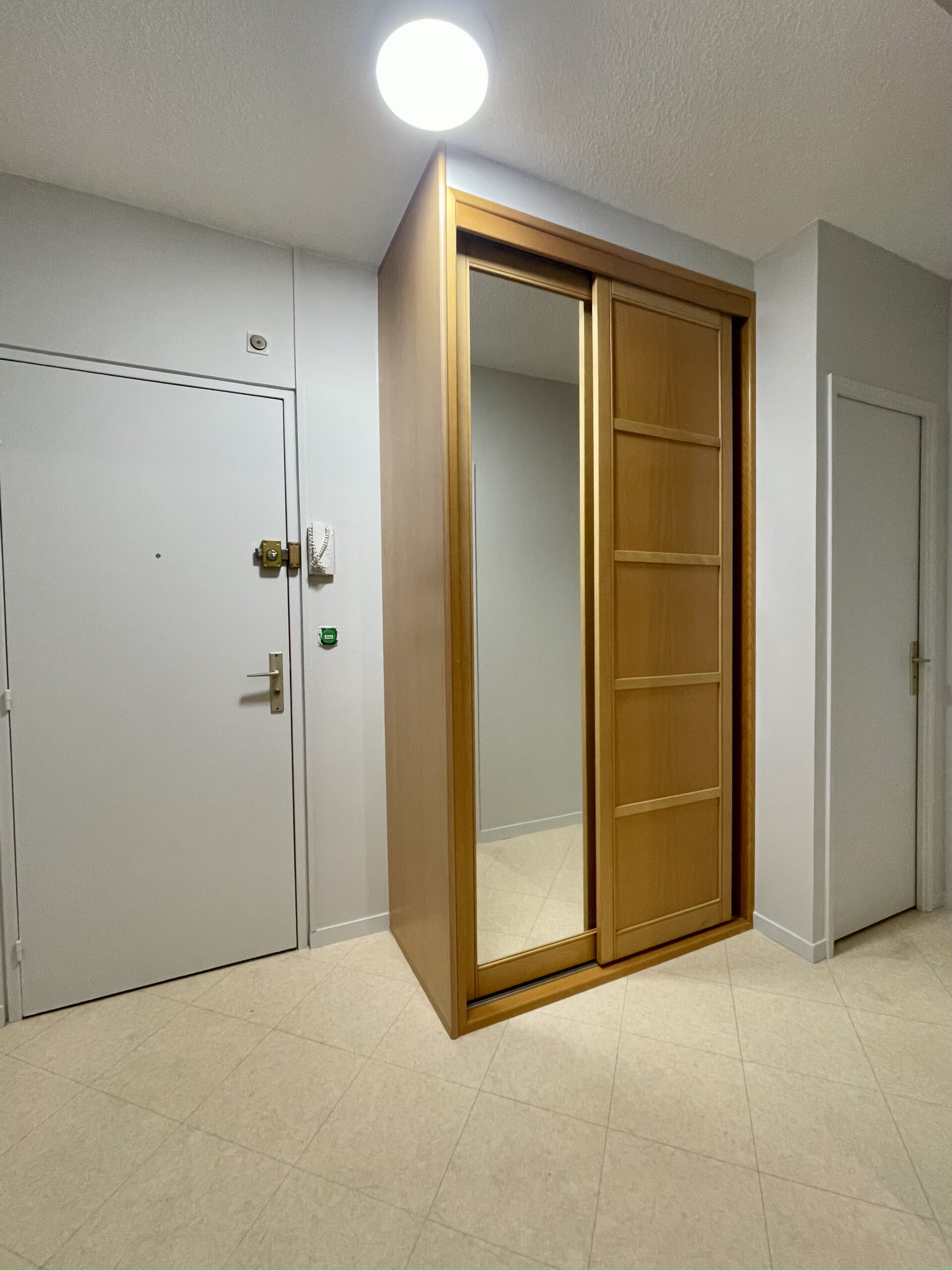 Entrée/couloir de l'appartement, les murs ont été repeints en gris clair, le sol est en dalles vinyle collées