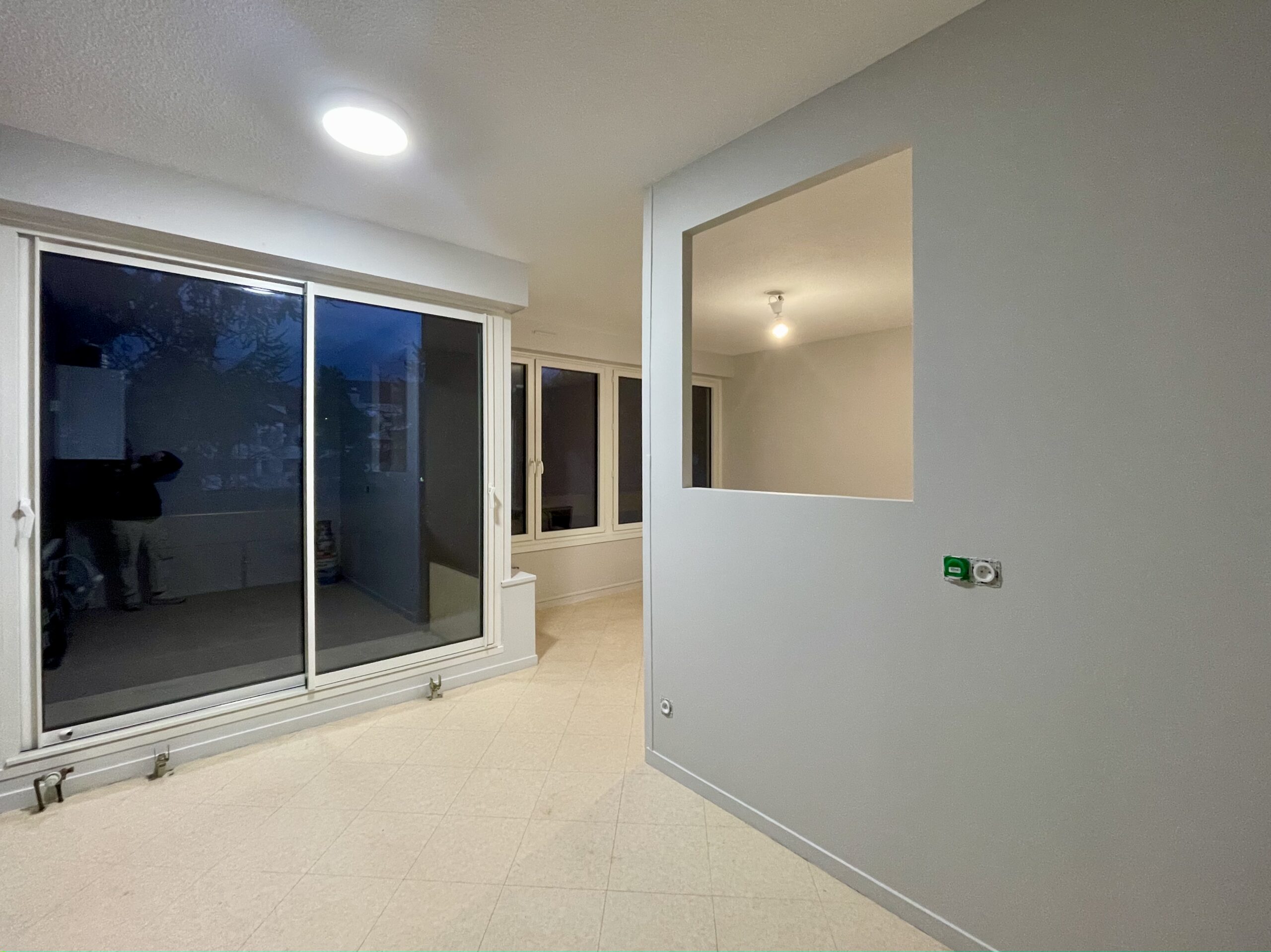 pièce de vie après travaux, la cuisine est ouverte sur le salon, une ouverture a été créée dans le mur de séparation entre les deux pièces, vue depuis la cuisine
